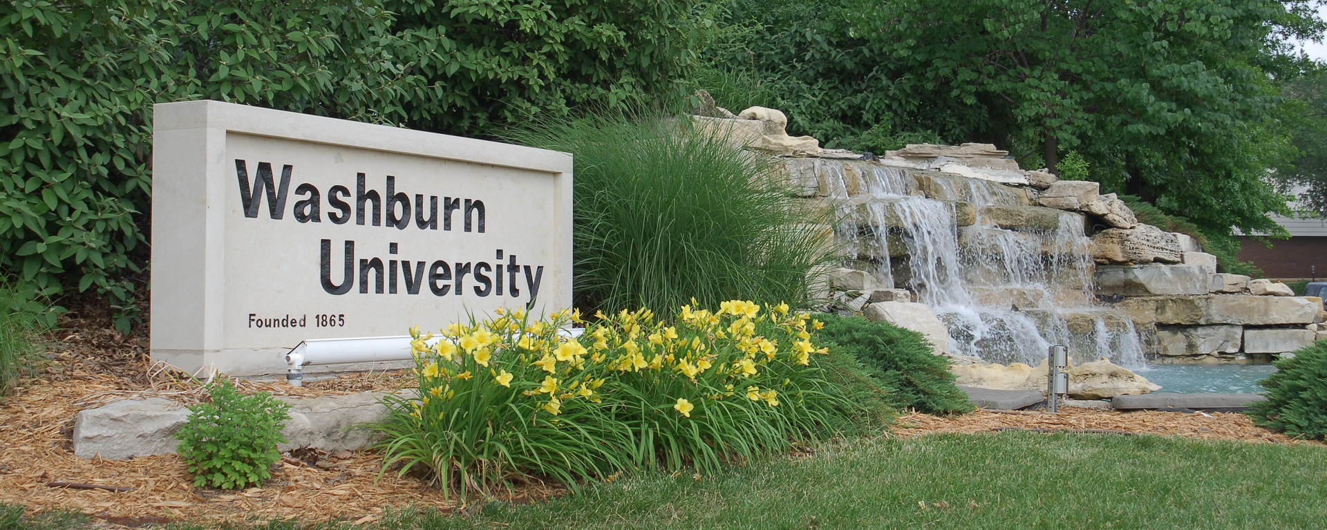 Washburn University sign next to a waterfall on the corner of campus.